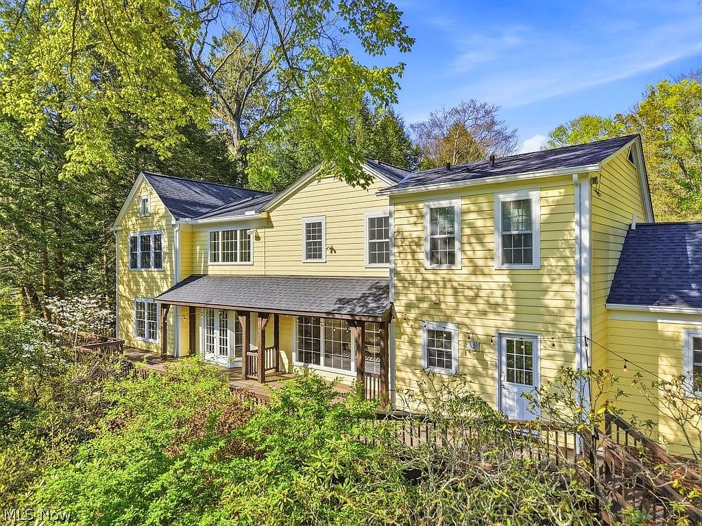 Rear elevation showing the second-story windows, back deck, and wooded slope behind the home